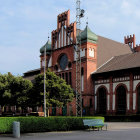 Majestic red brick castle with spires and clock tower in landscaped grounds