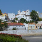 Futuristic cityscape with white buildings, domes, spires, greenery, and fountain