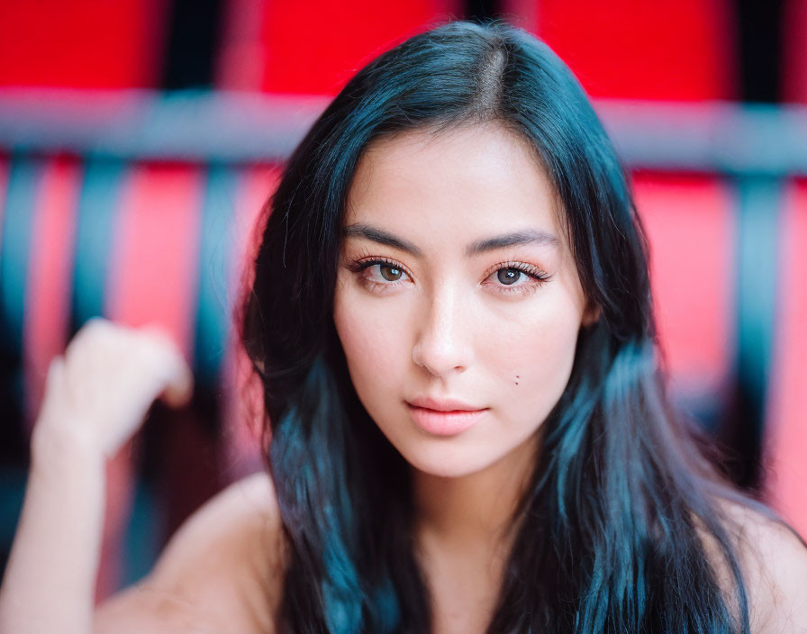 Portrait of woman with dark hair and brown eyes against red and black background