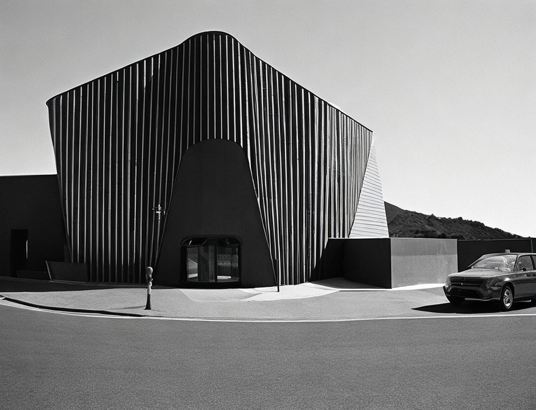 Monochrome image: modern wavy lines building next to old-fashioned car