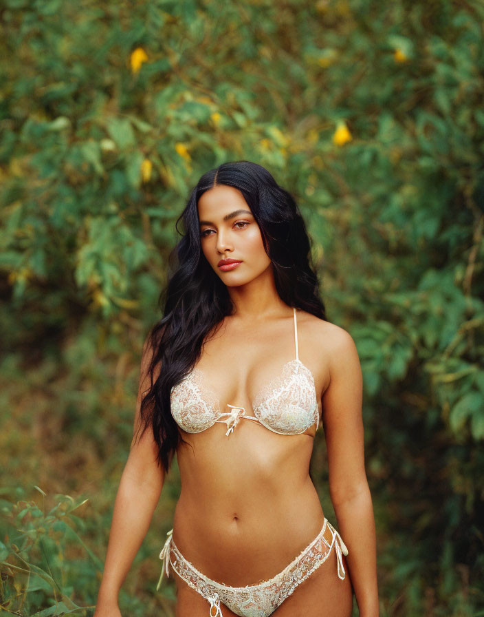 Woman in white lace bikini against green foliage with yellow flowers