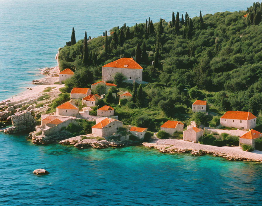 Tranquil coastal scene with red-roofed buildings and green trees by clear blue waters