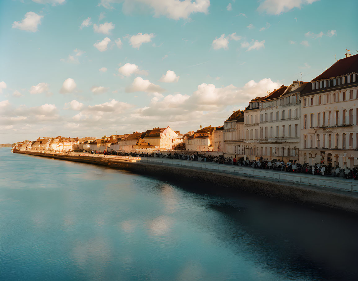 Historical buildings by tranquil riverside at sunset