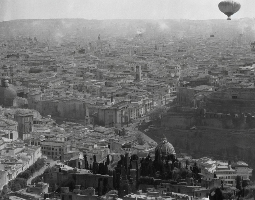 Monochrome aerial view of historic cityscape with domes and hot air balloon