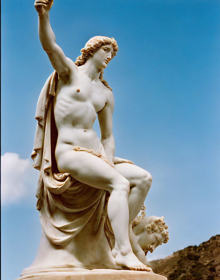 Classical nude male statue with drapery, set against sky and hill