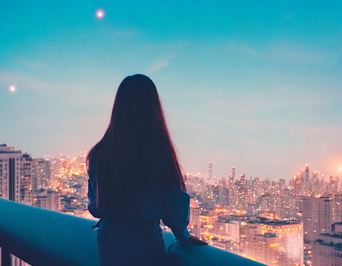 Long-haired person on balcony gazes at cityscape at twilight