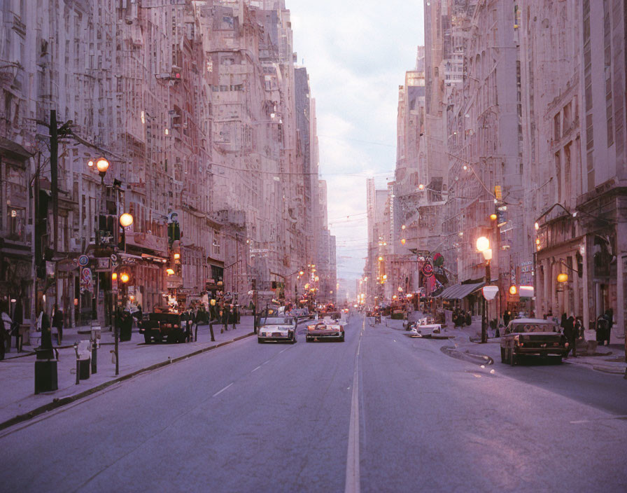 Vintage city street at twilight with cars, pedestrians, and tall buildings