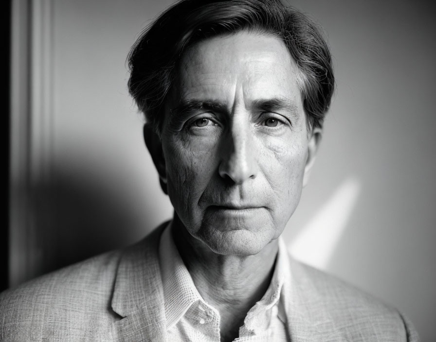 Middle-aged man in suit jacket with solemn expression in black and white portrait