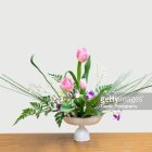 Pink Blossoms and Green Leaves in White Vase on Beige Background