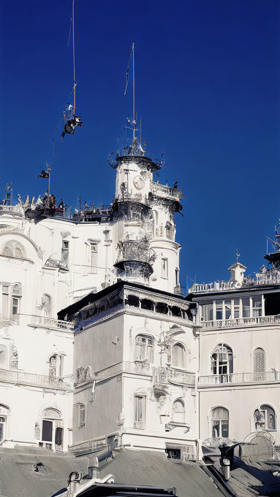 Ornate white building with sculptures and balconies under clear blue sky