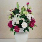 Pink and white rose bouquet in patterned vase with golden spoon on beige background