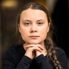 Young girl with braided hair and paint splatters, posing against bokeh background