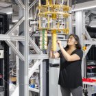 Striking futuristic woman with red and black hair in metallic attire among high-tech machinery