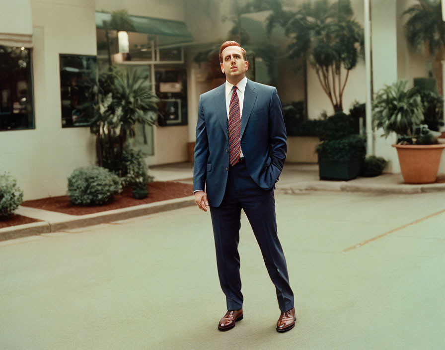 Man in Blue Suit and Striped Tie Contemplating Outdoors with Palm Trees