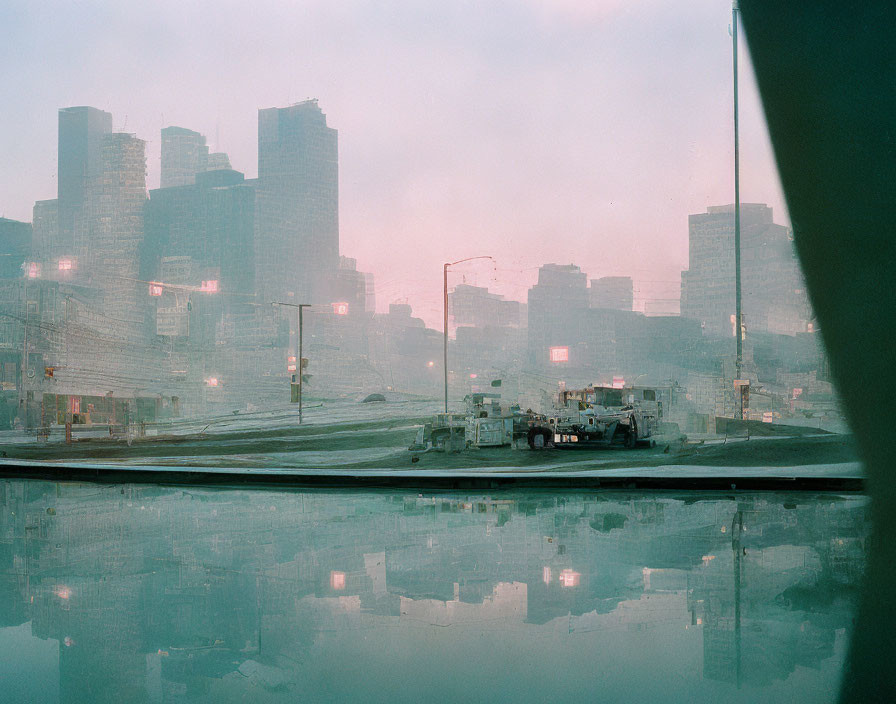 Foggy cityscape at dawn with skyscrapers, streetlights, construction vehicles, and reflective