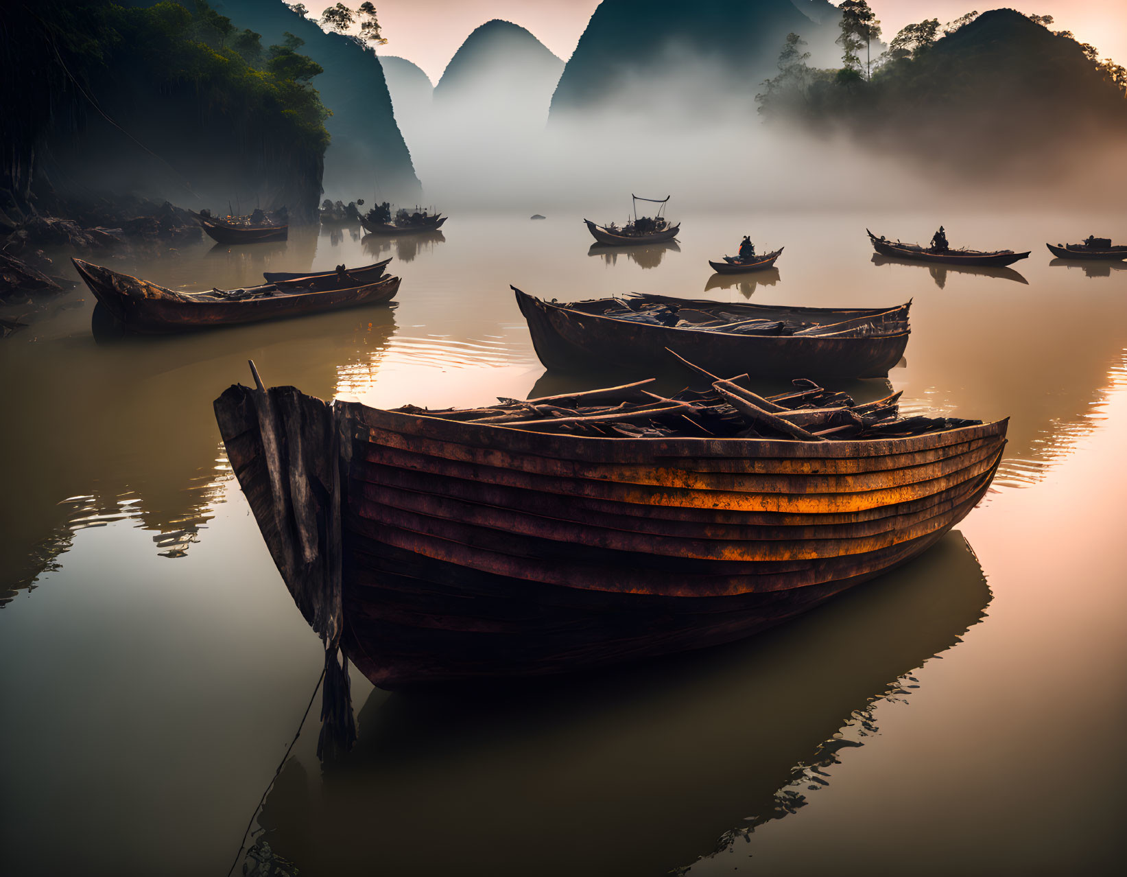 Weathered wooden boats on misty river with distant mountains reflected.