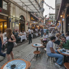 Vibrant street scene at dusk with traditional and modern attire, outdoor dining, pedestrians, ambient lighting