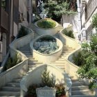 Women in Blue and Yellow Dresses on Stone Staircase with Classical Architecture