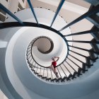 Detailed Blue Dress Woman on Spiral Staircase with Circular Window