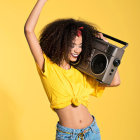 Vibrant green and purple hair woman with boombox in vintage outfit pose on yellow background