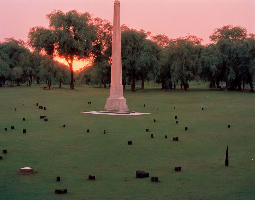 Monument in green field under pink sunset sky