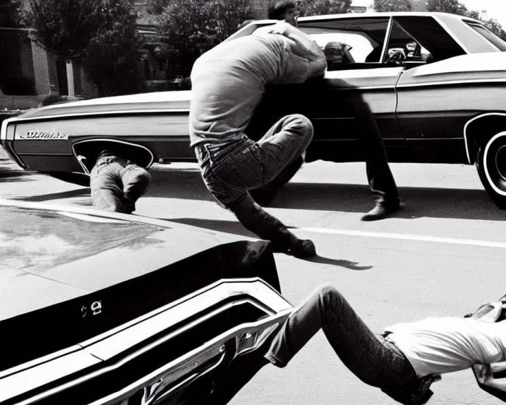 Monochrome image of men leaping over vintage cars, suggesting motion.