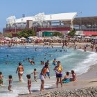 Colorful Coastal Scene with Beach-Goers, Buildings, Boats, and Birds