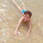 Child in Blue Swim Cap Smiling in Clear Water