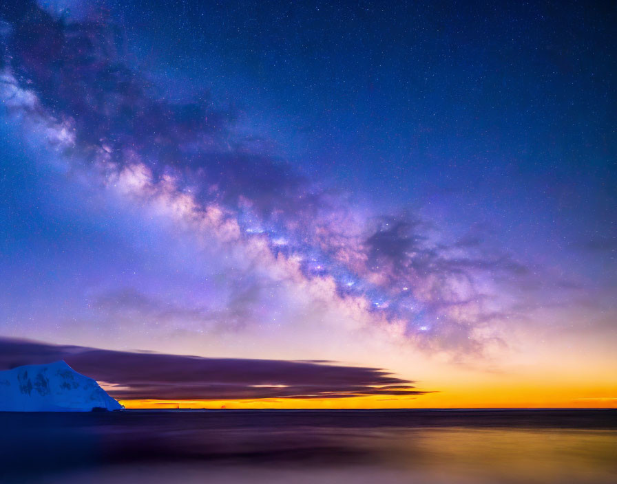 Twilight sky with stars and wispy clouds over tranquil sea & snow-covered landmass