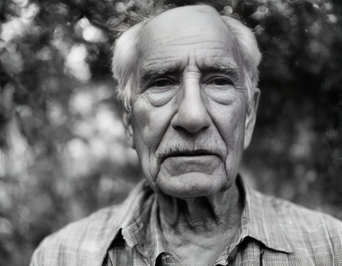 Elderly man with deep lines and white hair in natural setting