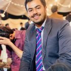 Bearded man smiling at festive celebration with confetti and balloons