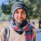 Intense man in knit cap and jacket against blurred background