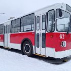 Vintage Red Trolleybus in Snowy Cityscape with Holiday Decorations