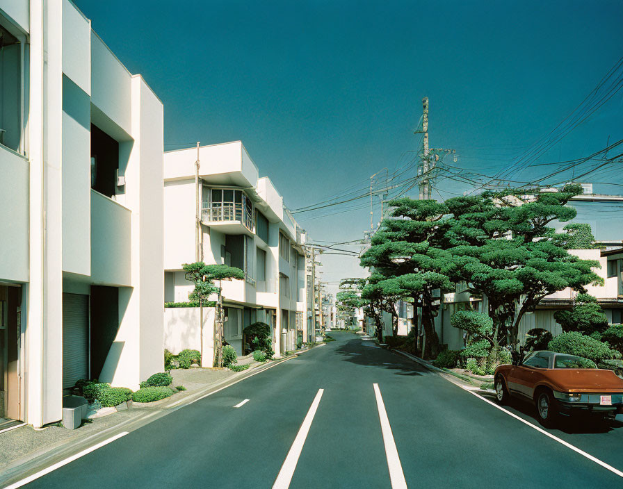 Serene suburban street with white buildings and parked car