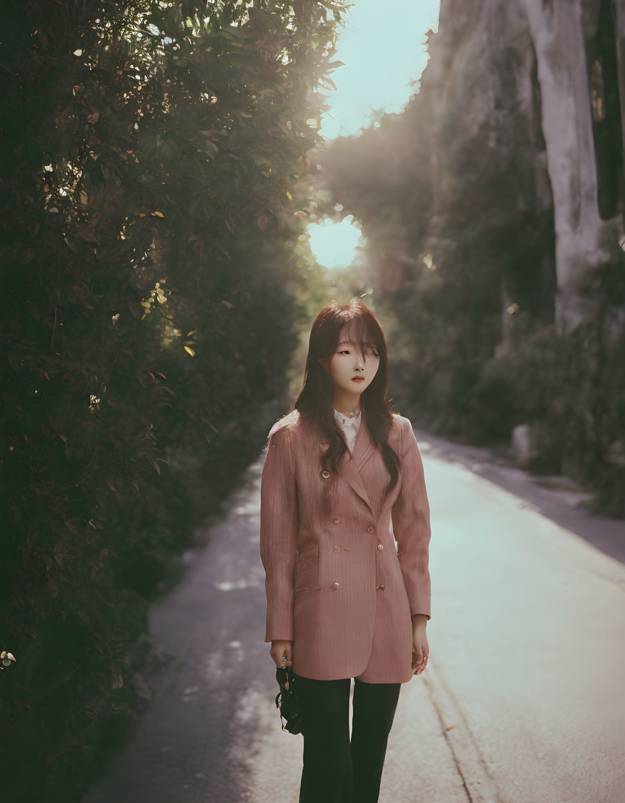 Woman in Pink Blazer Standing on Tree-Lined Path