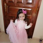 Young girl playing with toys and colorful eggs in a pink dress.