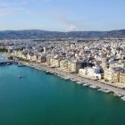 Scenic coastal town with white buildings, hills, and boat on clear day