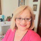 Blond woman in glasses smiles in soft-focus portrait