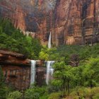 Rustic cliffside village with waterfall and lush greenery