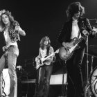 Group of musicians playing guitars and bass in sepia tones wearing fedoras