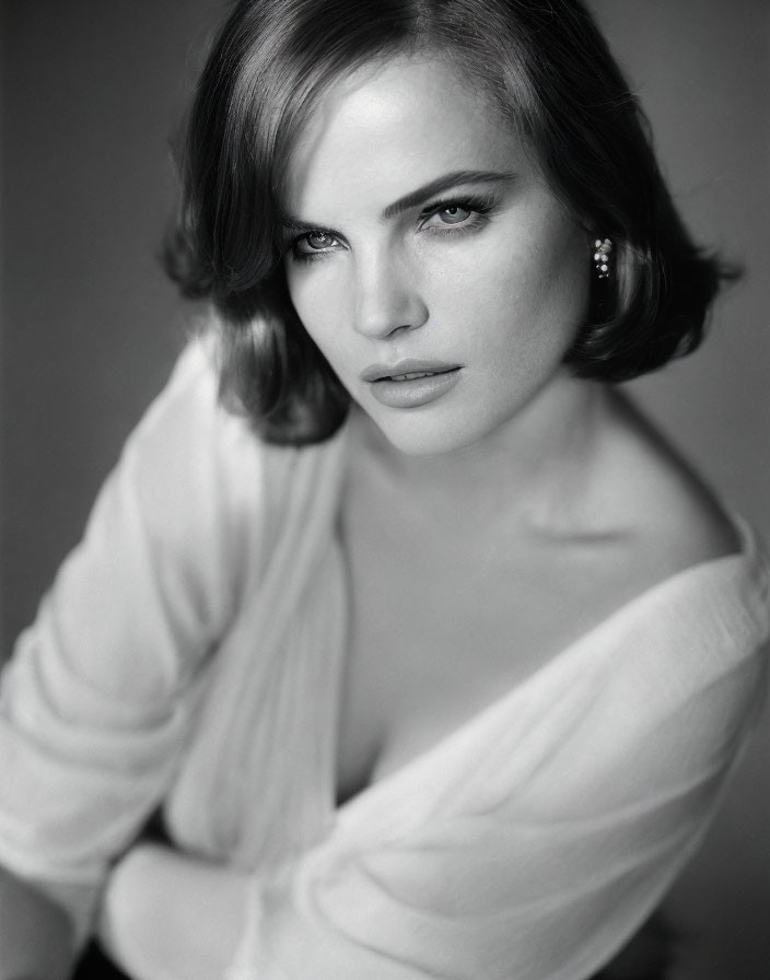 Monochrome portrait of woman with short hair and intense gaze wearing light blouse.