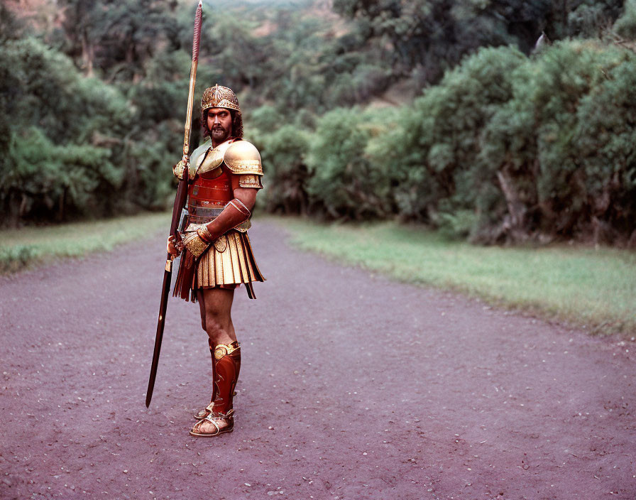 Ancient warrior in helmet, armor, and spear on dirt path among greenery