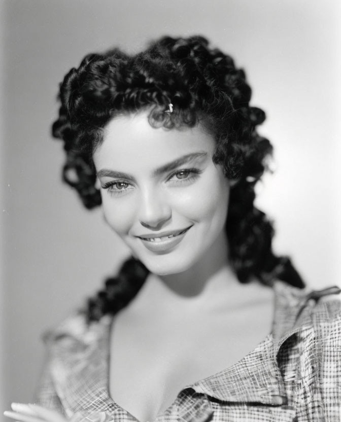 Monochrome portrait of smiling woman with curly hair in plaid top