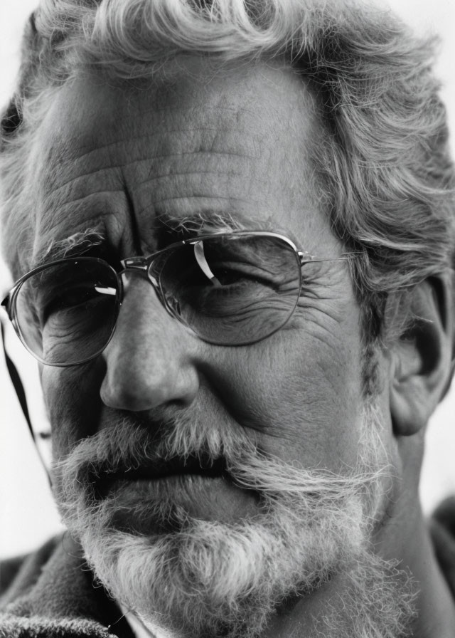 Monochrome close-up portrait of senior man with beard, mustache, and glasses