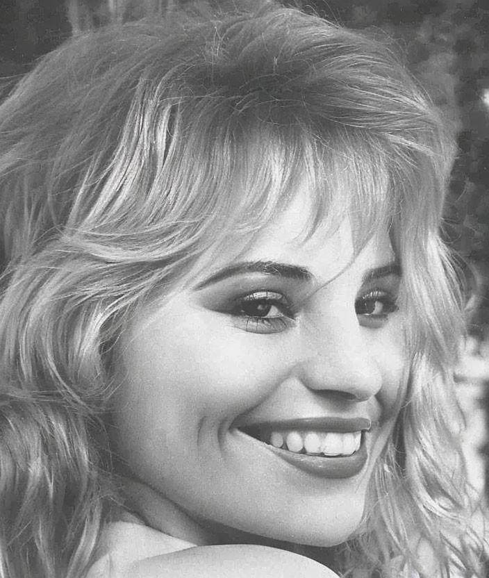 Monochrome image: Smiling woman with wavy hair and dimpled cheek