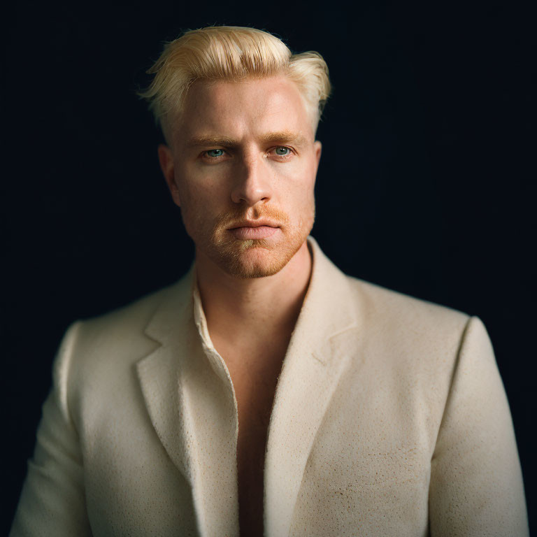 Blond man in light coat against dark background