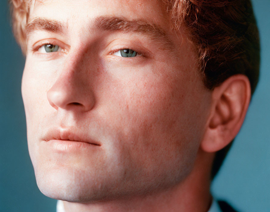 Man with Auburn Hair and Green Eyes Against Blue Background