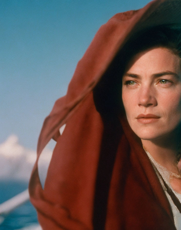 Serene woman in red scarf against blue sky and clouds