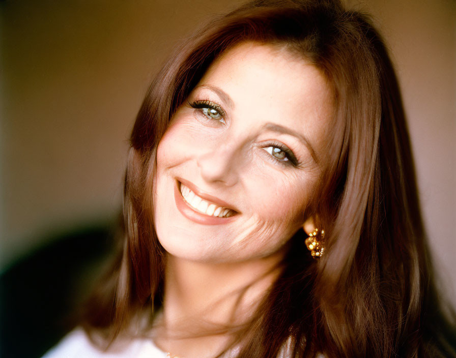 Smiling woman with long red hair and blue eyes in white outfit