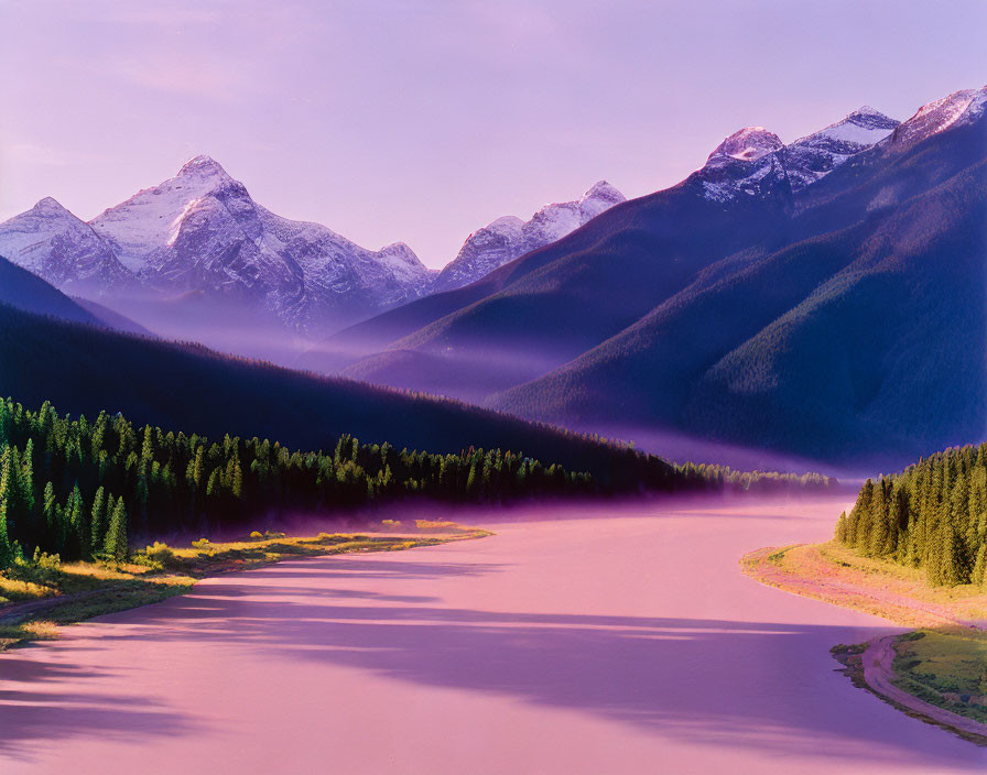 Misty river landscape with evergreen trees and snow-capped mountains